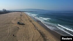 A few people are seen on the beach on the first day of a record heat wave, amid the global outbreak of coronavirus disease, in Hermosa Beach, near Los Angeles, Calif., Sept. 4, 2020.