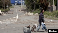 FILE - A man with a cart walks in a street in rebel-controlled city of Donetsk, Ukraine, July 18, 2015. Nearly 1.6 million internally displaced people in rebel-held parts of eastern Ukraine lack access to basic services and benefits, the U.N. refugee agency says.