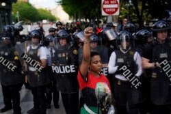 FILE - A demonstrator raises her fist to protest the death of George Floyd, near the White House, in Washington, May 30, 2020. Floyd, an African American, died after being restrained by Minneapolis police officers, triggering nationwide protests.