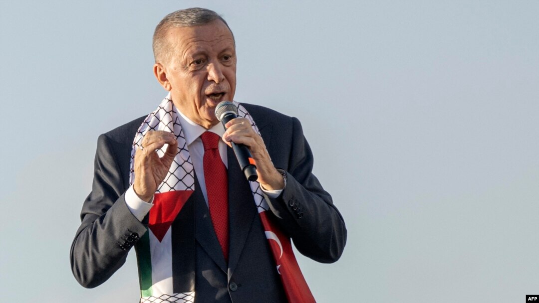 TOPSHOT - Turkish President Recep Tayyip Erdogan wears a scarf with both Turkish and Palestinian flags as he addresses a rally organised by the AKP party in solidarity with the Palestinians in Gaza, in Istanbul on October 28, 2023.