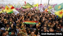 People gesture while others wave Kurdish flags 