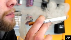 FILE - A sales associate demonstrates the use of an electronic cigarette and the smoke-like vapor that comes from it, in Aurora, Colorado, March 2, 2011.