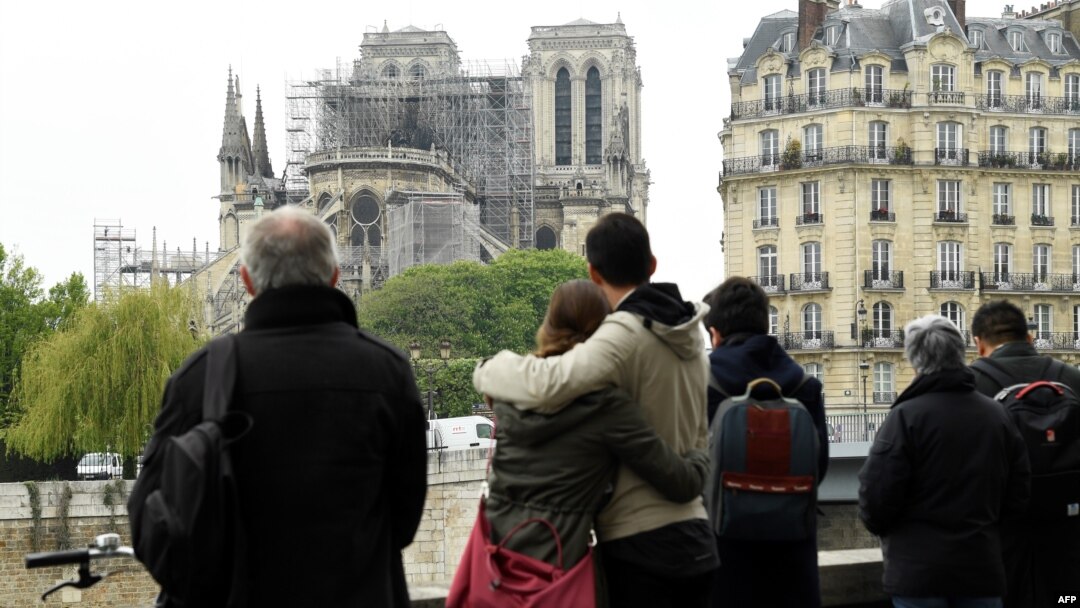 People hug while looking at Notre-Dame-de-Paris in the aftermath of a fire that devastated the cathedral, April 16, 2019. 