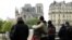 FILE - People hug while looking at Notre-Dame-de-Paris in the aftermath of a fire that devastated the cathedral, April 16, 2019. 