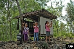 FILE - Elementary school students, aiming to study online using their smartphones, search for a better internet signal than in their village, on Temulawak hill in Yogyakarta, Indonesia, May 8, 2020.