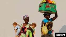 Hawkers walk past each other in the capital Luanda, Aug. 28, 2012. 