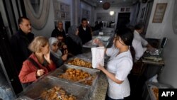 FILE—An employee serves pastry to a customer at a bakery in Tunis during the Muslim holy fasting month of Ramadan on March 29, 2024, amid a shortage of sugar supplies in the country.