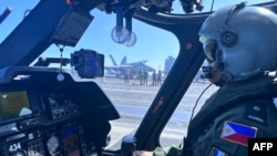 2023年1月4日，在与美国在南中国海进行联合巡逻演习时，一名飞行员对在卡尔文森号航母甲板上的一架菲律宾海军直升机上执行最后检查。（法新社照片）
