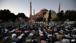 Muslims offer evening prayers outside the Byzantine-era Hagia Sophia, one of Istanbul's main tourist attractions in the historic Sultanahmet district of Istanbul, July 10, 2020. 