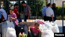 Seorang anak Suriah duduk di samping barang-barang milik keluarganya selagi menanti kendaraan jemputan setelah tiba di negara tetangga, Turki.