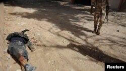 A fighter with forces led by renegade former Libyan general Khalifa Haftar stands by the body of an Ansar al-Shariah militiaman killed during clashes in Benghazi Oct. 15, 2014.