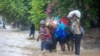 People cross a flooded street during the passing of Tropical Storm Laura in Port-au-Prince, Haiti, Aug. 23, 2020.