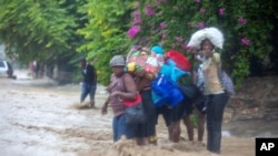 Ljudi prelaze poplavljenu ulicu tokom prolaska tropske oluje Lora u Portopensu, Haiti, 23. avgust 2020.