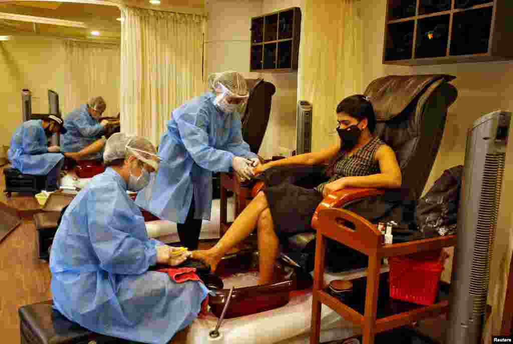 Beauticians wearing protective gear tend to their customers inside a parlor at a shopping mall after authorities allowed the reopening of malls, during an extended nationwide lockdown to slow the spread of the COVID-19, in Ahmedabad, India.