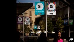 Banners urging support for a "yes" vote in a Catalan independence referendum hang on poles as people walk along a street in Sabadell, near Barcelona, Spain, Sept. 7, 2017. 