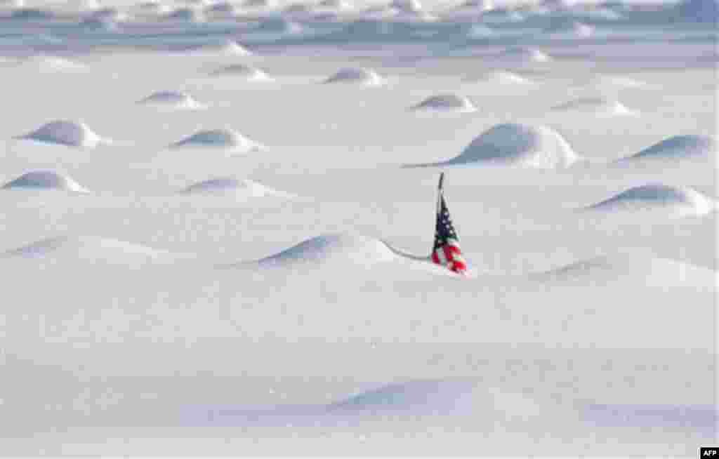 January 27: A flag pokes above the snow around mounds of covered grave markers in Veterans Memorial Field in East Hartford, Conn., after another winter storm. (AP/Jessica Hill)