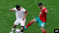 L'Iranien Masoud Shojaei et le Marocain Younes Belhanda lors du match du groupe B entre le Maroc et l'Iran à la Coupe du monde de football 2018 à Saint-Pétersbourg, Russie, le 15 juillet 2018.