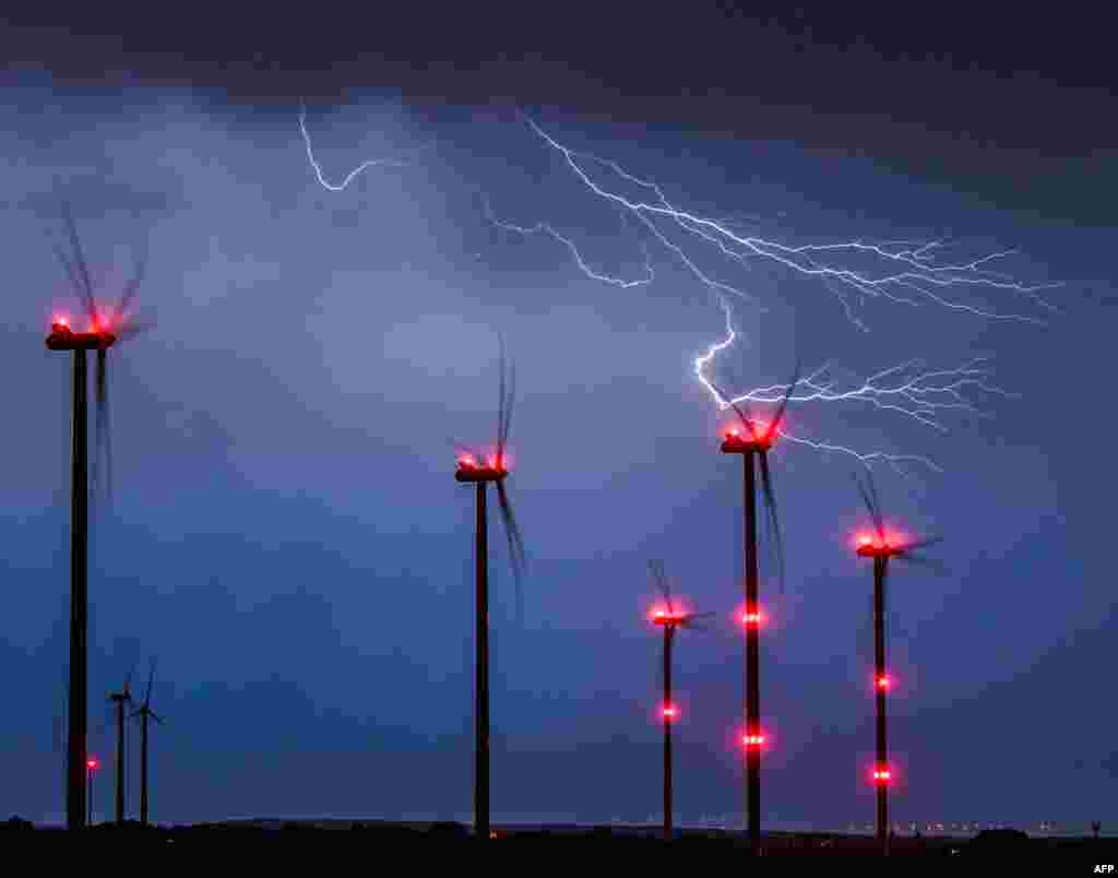 Lightning strikes close to wind turbines in a wind energy park during a thunderstorm near Sieversdorf in eastern Germany.