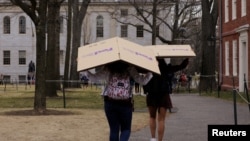 FILE - Students carry boxes to their dorms at Harvard University, after the school asked its students not to return to campus after Spring Break, March 10, 2020, in Cambridge, Massachusetts, U.S. 