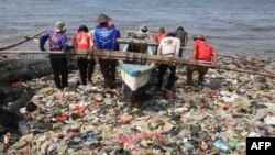 Nelayan Indonesia mendorong perahunya di antara sampah plastik yang memenuhi pantai Sukaraja di Bandar Lampung, 8 September 2019. (Photo by PERDIANSYAH / AFP)