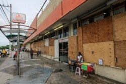 شدید بارشوں اور تیز ہواؤں سے بچنے کے لیے لوگوں نے دکانوں کے آگے لکڑی کے تختے لگا دیے ہیں۔ 27 اکتوبر 2020