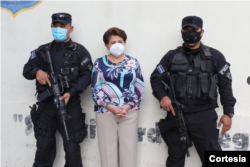 La exalcaldesa de San Salvador Violeta Menjívar flanqueada por dos policías tras su arresto el 22 de julio de 2021 por acusaciones de corrupción. Foto cortesía FGR de El Salvador.