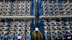 FILE - A worker climbs stairs among some of the 2,000 pressure vessels that will be used to convert seawater into fresh water through reverse osmosis in a desalination plant in Carlsbad, Calif.