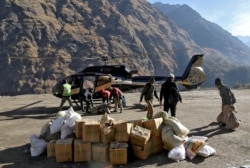 People load relief goods onto a helicopter for distribution in the affected areas, after a flash flood swept a mountain valley destroying dams and bridges, in Dhak village in Chamoli district, in northern state of Uttarakhand, India, Feb. 12, 2021.