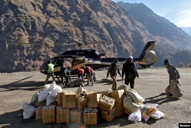 People load relief goods onto a helicopter for distribution in the affected areas, after a flash flood swept a mountain valley destroying dams and bridges, in Dhak village in Chamoli district, in northern state of Uttarakhand, India, Feb. 12, 2021.
