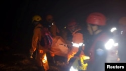 Rescue workers carry a body bag containing a victim following the collapse of an illegal gold mine at Bolaang Mongondow regency in North Sulawesi, Indonesia, Feb. 26, 2019, in this photo taken by Antara Foto.