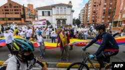 Colombianos ondean la bandera nacional durante una manifestación en oposición a los bloqueos de carreteras y la violencia, luego de un mes de protestas nacionales, en Bogotá, el 30 de mayo de 2021.