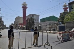 Policemen wearing face masks stand guard on a deserted street enforcing a nationwide coronavirus lockdown, in Karachi, Pakistan, May 1, 2020.