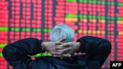 FILE - An investor looks at a screen showing stock market movements at a securities company in Hangzhou, in eastern China's Zhejiang province on Feb. 8, 2024. 