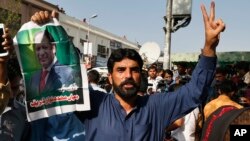 A supporter of former Pakistani Prime Minister Nawaz Sharif holds his picture and makes a victory sign after a court ruling, outside the Islamabad High Court in Islamabad, Pakistan, Sept. 19, 2018. 