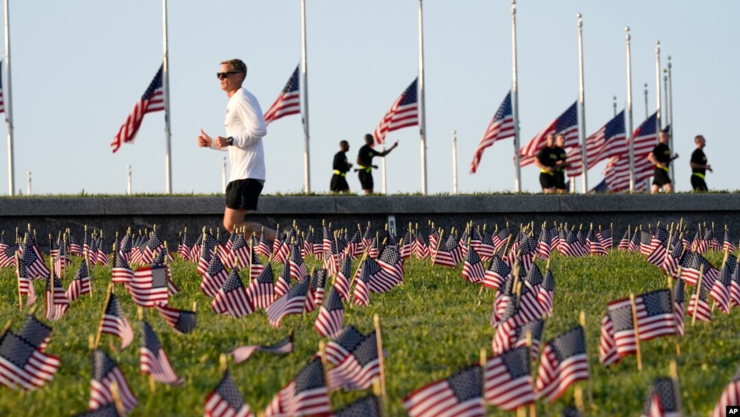 Morning joggers look over small flags that activists from the COVID Memorial Project placed on the grounds of the National Mall to mark the deaths of 200,000 lives lost in the U.S. to COVID-19, Sept. 22, 2020 in Washington.
