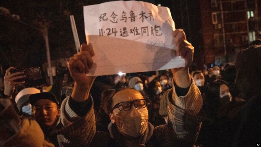 一名抗议者11月27日晚间在北京手举白纸抗议，上面写道：“纪念乌鲁木齐11.24遇难同胞”。自11月25日以来，中国多个城市爆发街头抗议，表达对政府“清零”政策的不满，还有抗议民众高喊要求“习近平下台”。（2022年11月27日）(photo:VOA)