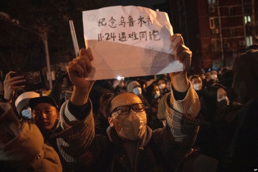 北京市民手举纪念乌鲁木齐11.24死难者的标语参加示威活动。（2022年11月27日）(photo:VOA)