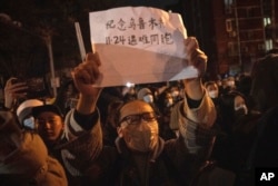 北京市民手举纪念乌鲁木齐11.24死难者的标语参加示威活动。（2022年11月27日）
