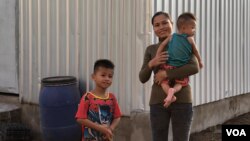 Sim Ark, 29, holds her five-month-old baby Ham Ya Oudom, as Ham Yarith, 5 years old, stnads nearby at their home in Sneang village, Svay Ta Yean commune, Svay Rieng province, Cambodia, on October 11, 2019. (Khan Sokummono/VOA Khmer)