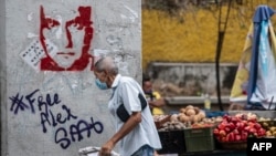 Un hombre pasa junto a un grafiti que exige la libertad del empresario colombiano Alex Saab, en Caracas, el 23 de febrero de 2021. 