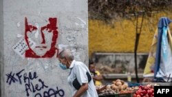 Un hombre pasa junto a un grafiti que exige la libertad del empresario colombiano Alex Saab, en Caracas, el 23 de febrero de 2021. 