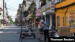 A man picks up groceries through a barrier in a quarantine area amid (COVID-19) in Hanoi.