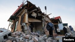 Local residents remove debris and carry belongings out of a shop destroyed in recent shelling in the course of Russia-Ukraine conflict in Donetsk, Russian-controlled Ukraine, Jan. 10, 2023. 