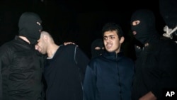Alireza Mafiha, second left, leans his head on the shoulder of a security officer moments before his execution along with Mohammad Ali Sarvari, second right, in Tehran, Iran, Jan. 20, 2013. 