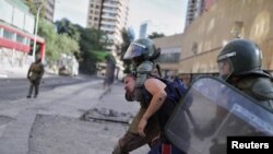 Riot police detain a demonstrator during a protest against Chile's government, in Santiago, Chile Dec. 10, 2019.