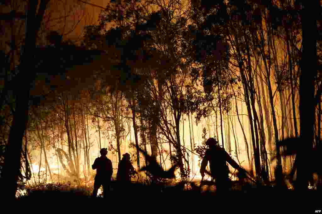 Firefighters battle a fire on Fingerfield Road in the Deepwater National Park area of Queensland, Australia.