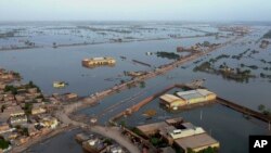 FILE - Homes are surrounded by floodwaters in Sohbat Pur city, a district of Pakistan's southwestern Baluchistan province, Aug. 29, 2022. 