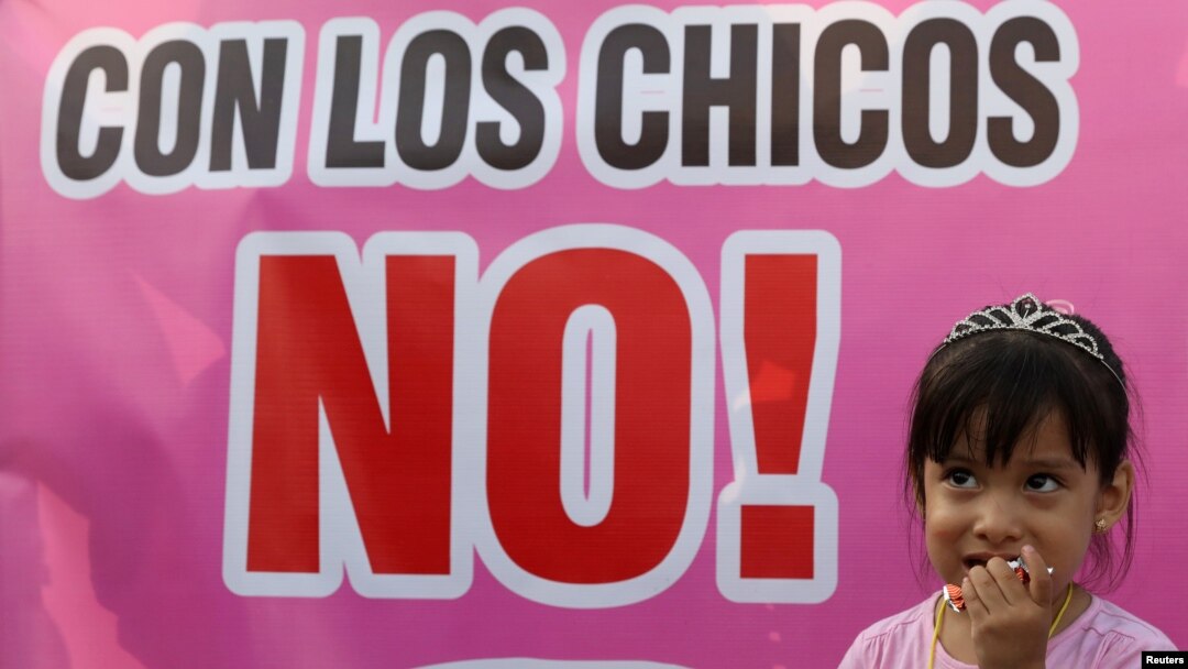 Seroang anak berdiri di samping sebuah poster beruliskan: 'Katakan Tidak Pada Anak' dalam demonstrasi memprotes kekerasan pada anak di Lima, Peru, 28 Februari 2018.