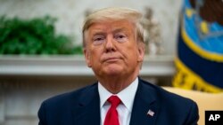 FILE - President Donald Trump listens to a question from a reporter, in the Oval Office of the White House, in Washington, Feb. 12, 2020. 