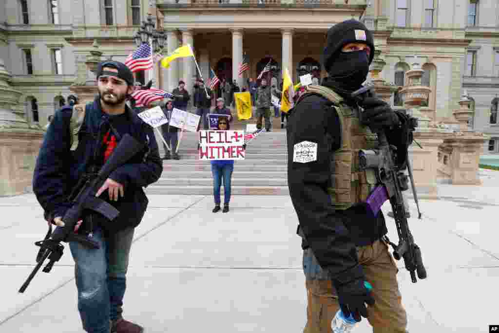 Protesters carry rifles near the steps of the Michigan State Capitol building in Lansing, Michigan, April 15, 2020, to show their displeasure with Gov. Gretchen Whitmer's orders to keep people at home and businesses locked during the coronavirus outbreak.